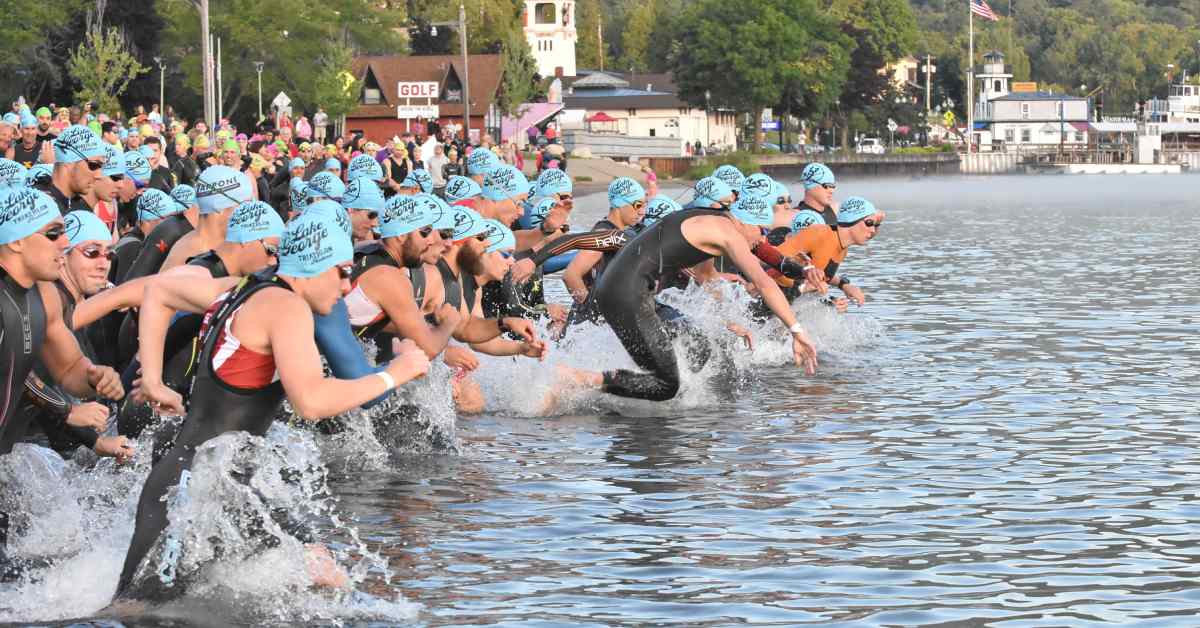 people charging into a lake for a triathlon swimming event