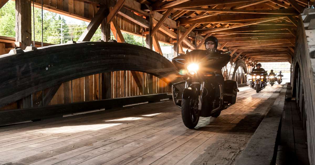 motorcyclists riding through a covered bridge