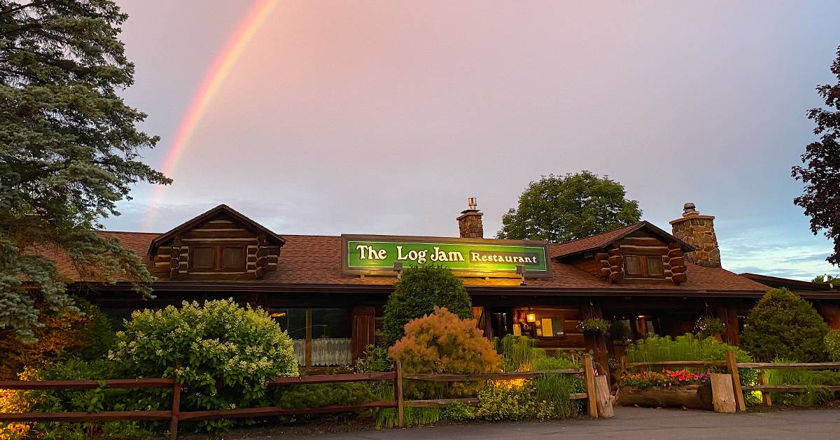 exterior of the log jam restaurant in lake george with a rainbow over it