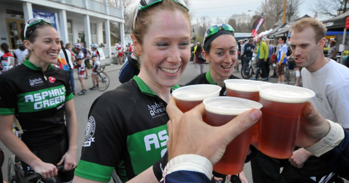 cyclists holding up beer after a race