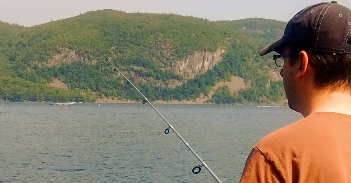 man with fishing pole fishing in lake george