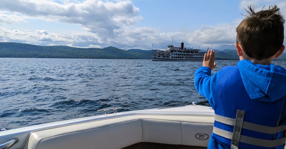 kid waves to lake george steamboat from boat