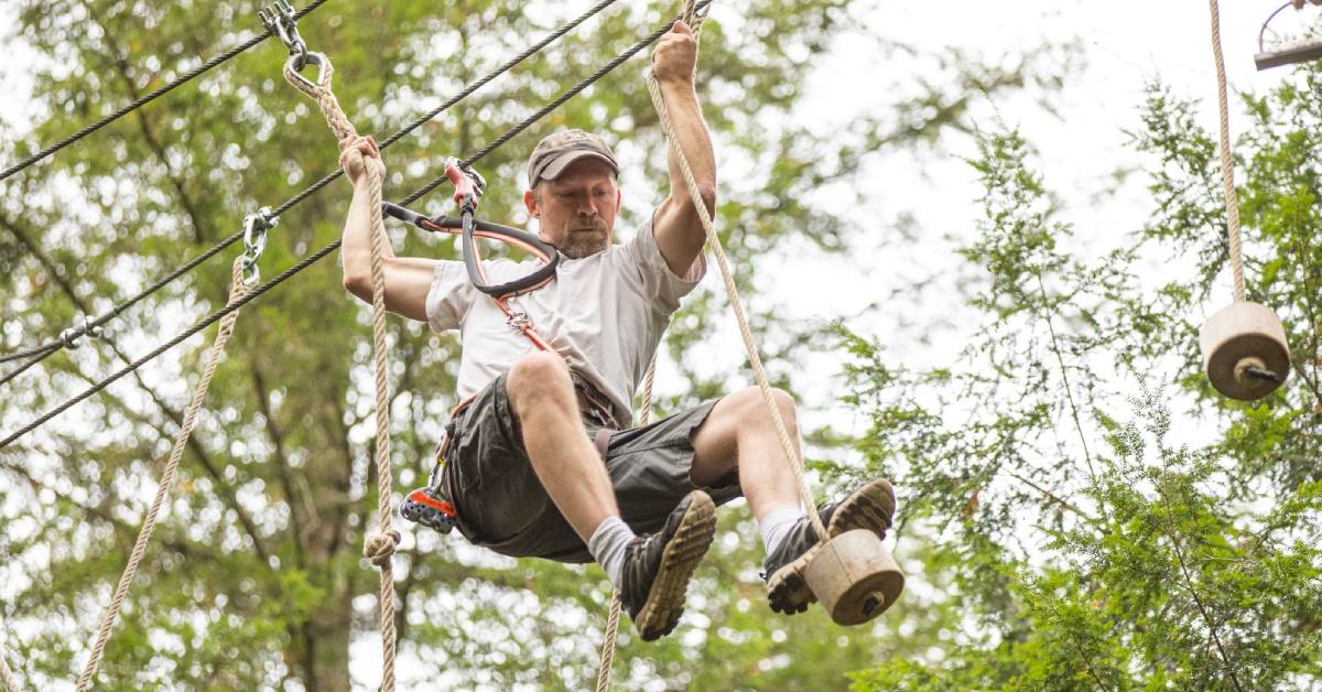 man traverses treetop adventure course