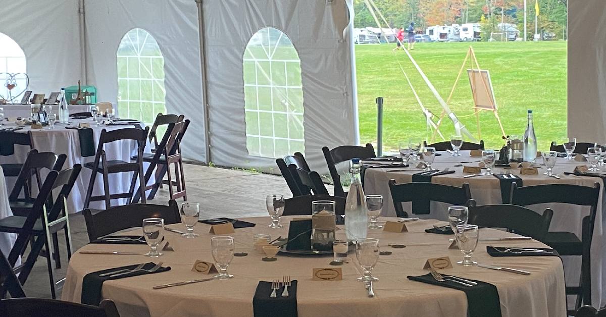 tables set up for wedding in tent with campers in the background