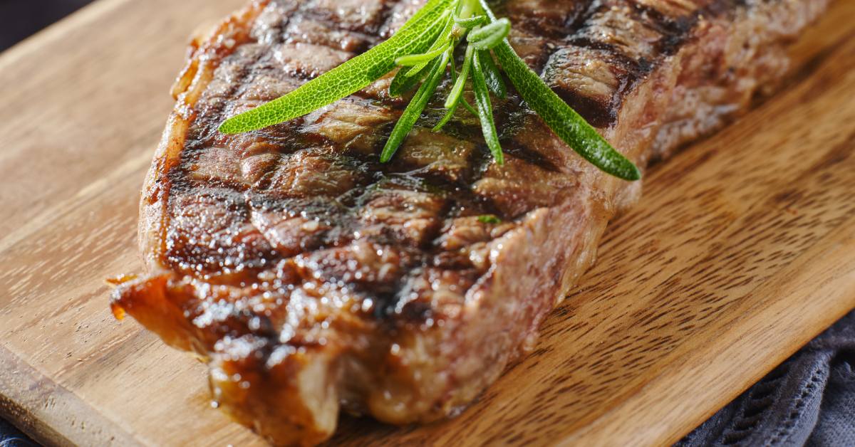 steak on cutting board with rosemary garnish