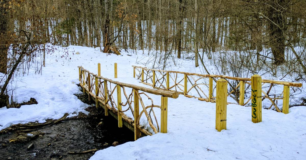 bridge over water in woods in the winter at halfway brook trail