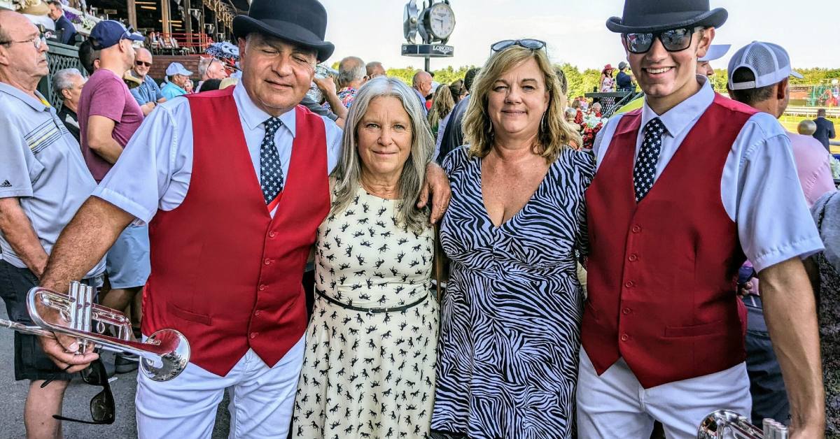 two women pose with trumpet players at the track