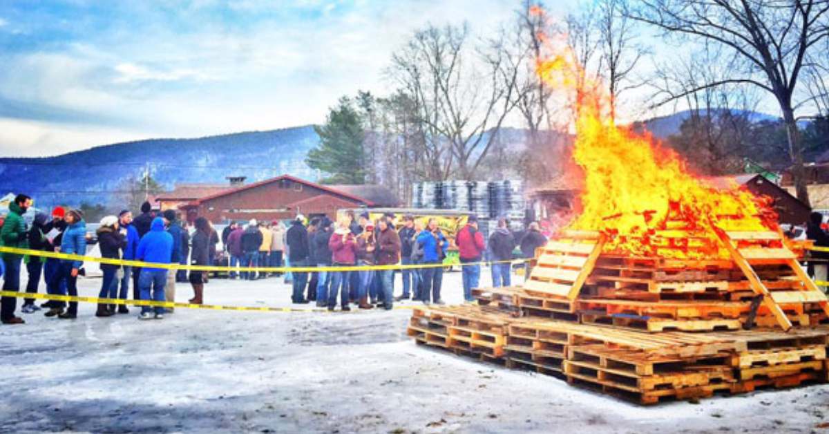 Large bonfire on snowy ground next to a crowd of people