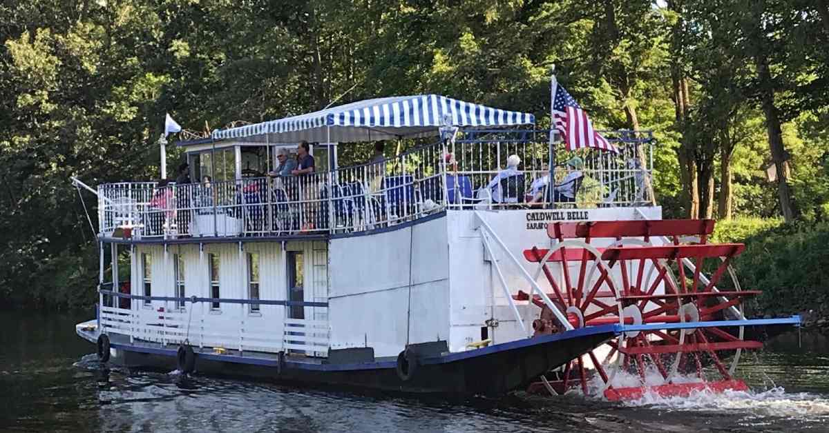 Sternwheel paddleboat on a canal next to land
