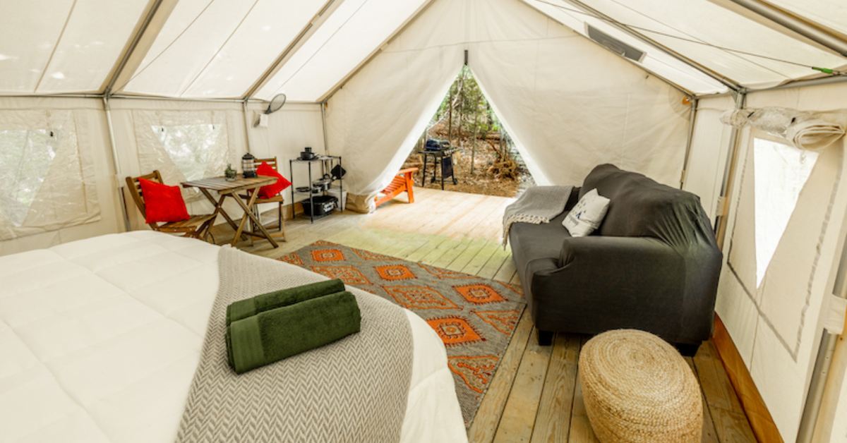 Inside of glampful tent with a bed, couch, table, and rug