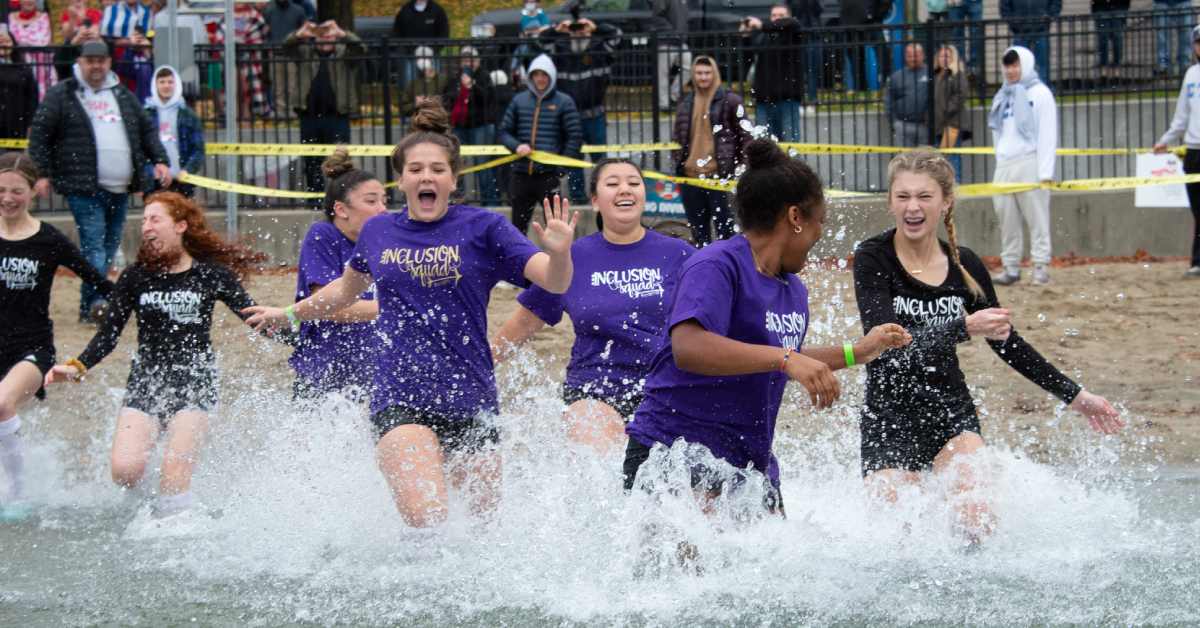 Group of girls running into lake from beach