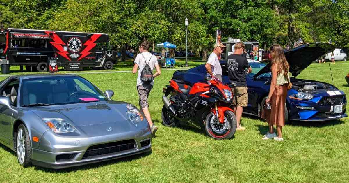 four people checking out a car show on a lawn