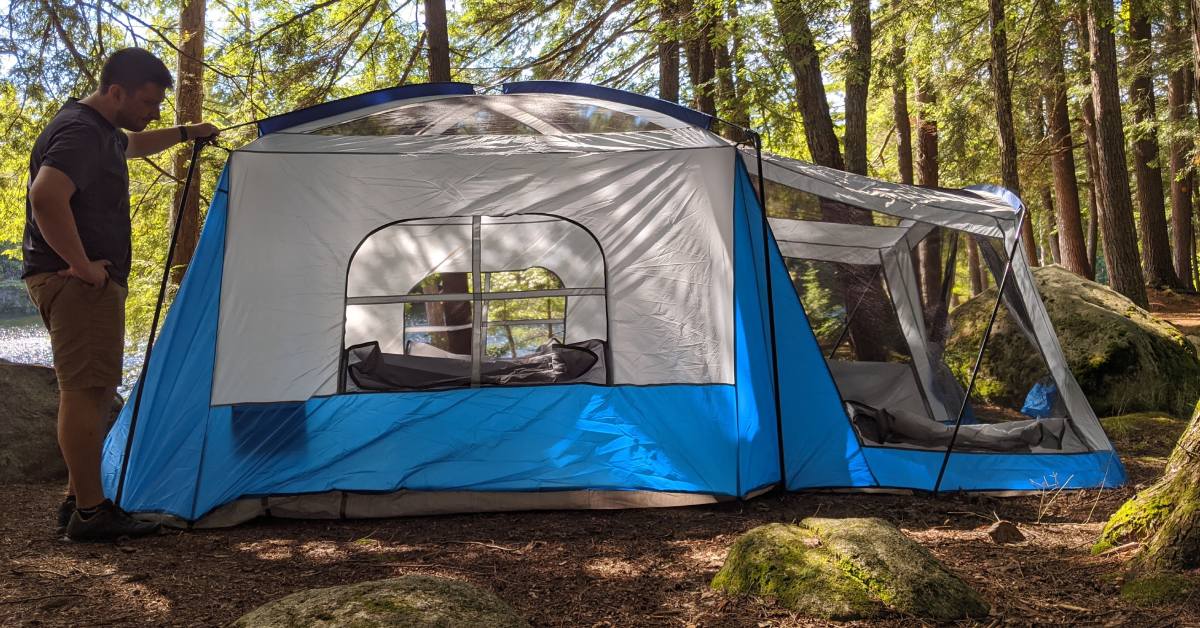 man by camping tent in woods