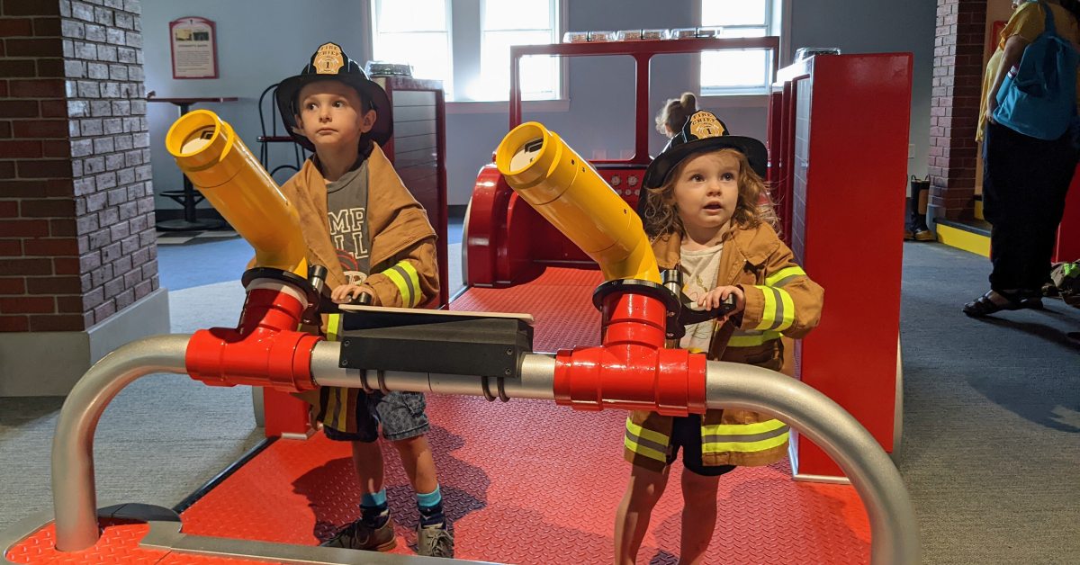 kids dressed as firemen on a firetruck at children's museum at saratoga