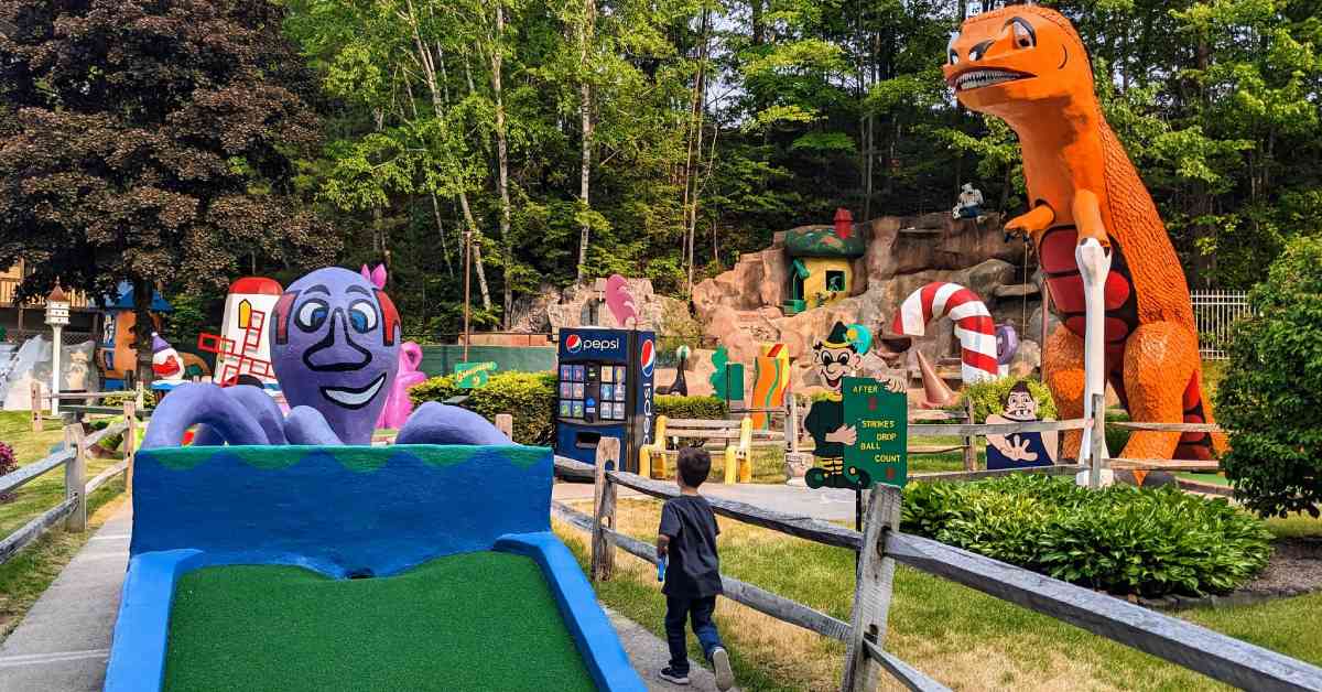 young boy walking by a mini golf course attraction