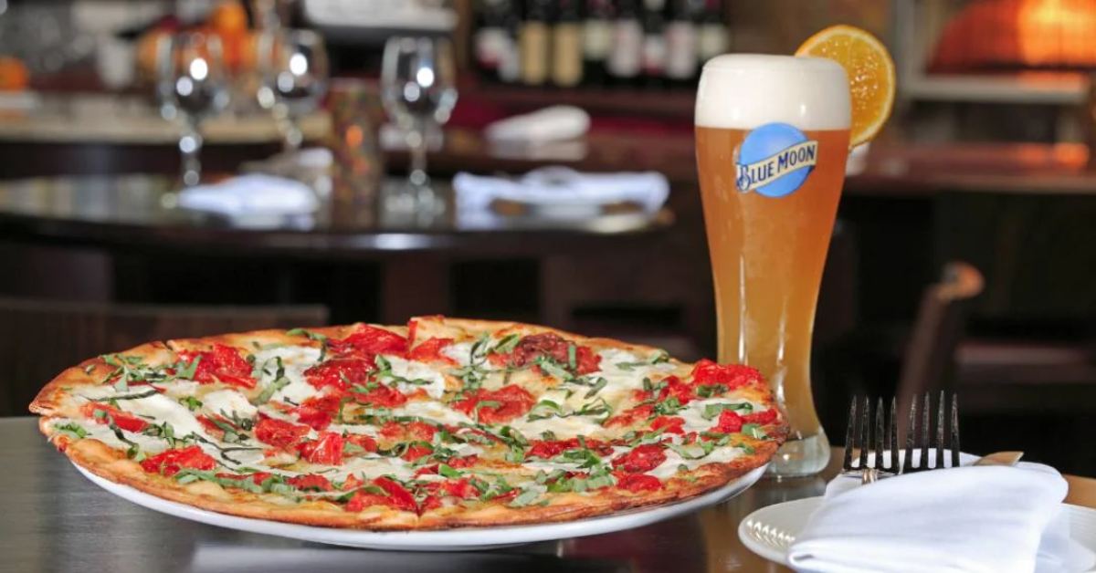 pizza on a table next to a glass of beer