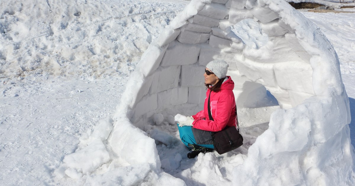 woman sits in snow shelter