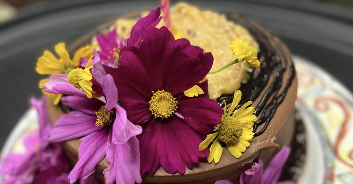 Closeup of a chocolate dessert with purple and yellow flowers on top