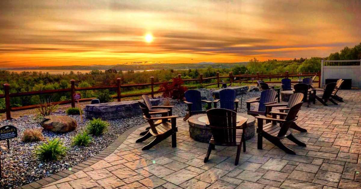 Patio with chairs and firepits overlooking a sunset landscape