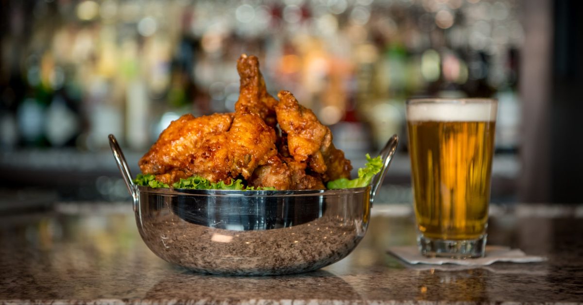 Bowl of jumbo wings next to a pint of beer