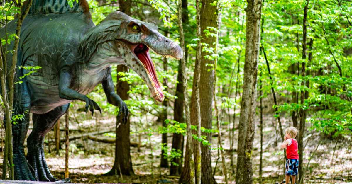 Little boy standing in front of dinosaur