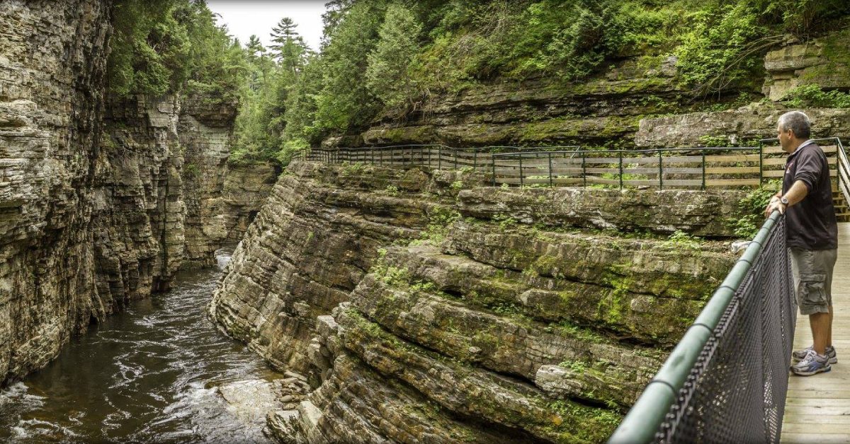 man looks out from walkway at ausable chasm