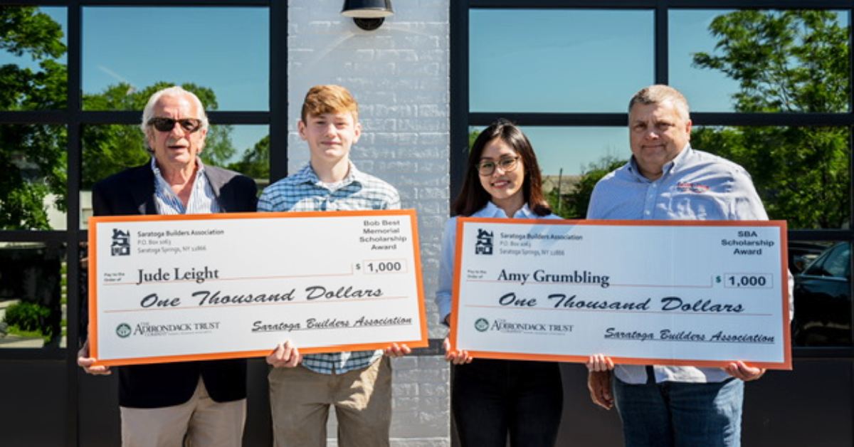 two students are awarded large checks and pose for picture with two older men