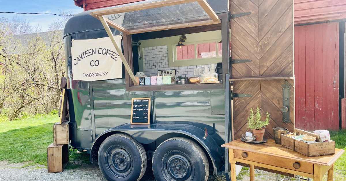 canteen coffee co's green mobile business trailer with a wooden table sitting beside it