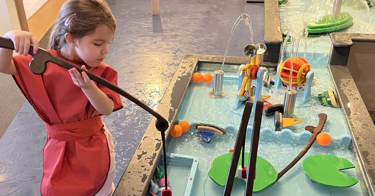 girl plays with interactive water exhibit at north country children's museum