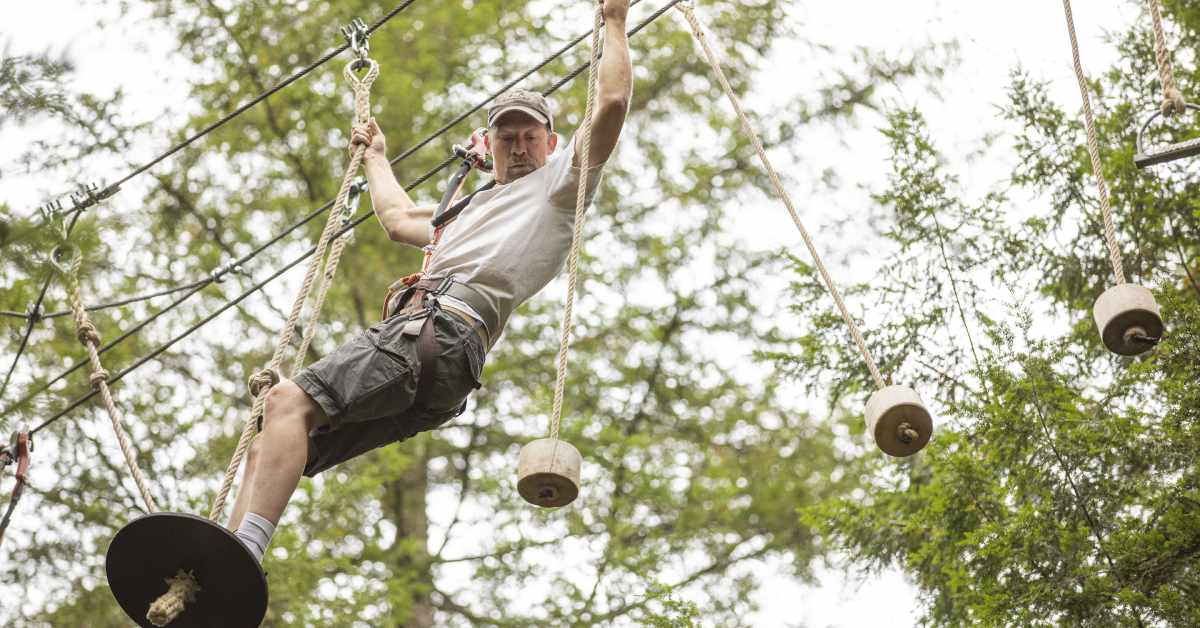 Man standing on a disc with rope attached to it suspended in the air. 