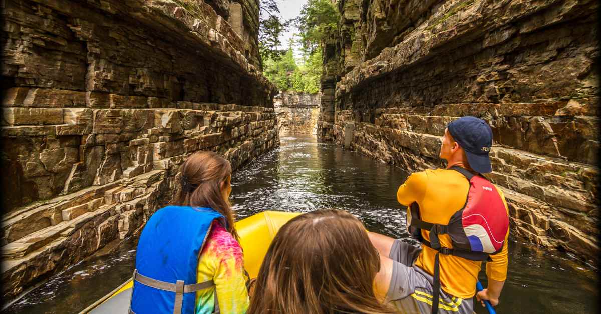 3 people on a raft floating through a chasm 