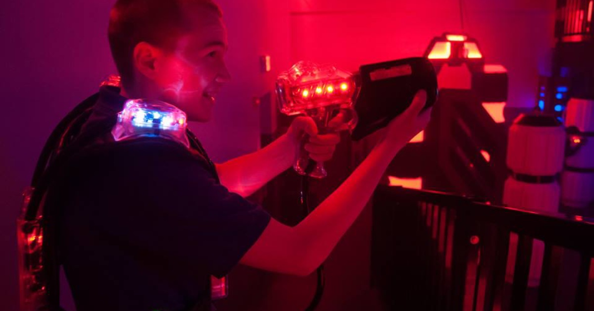 Close up of kid holding laser tag gun with red background lighting