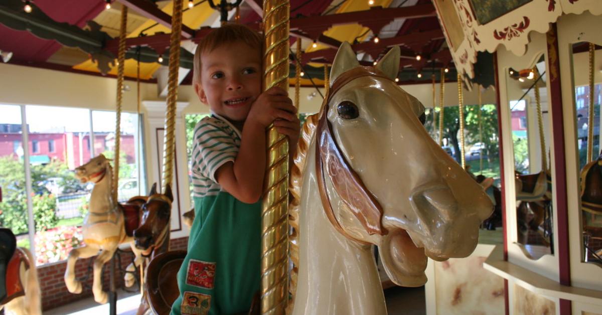 Close up of smiling kid riding carousel horse