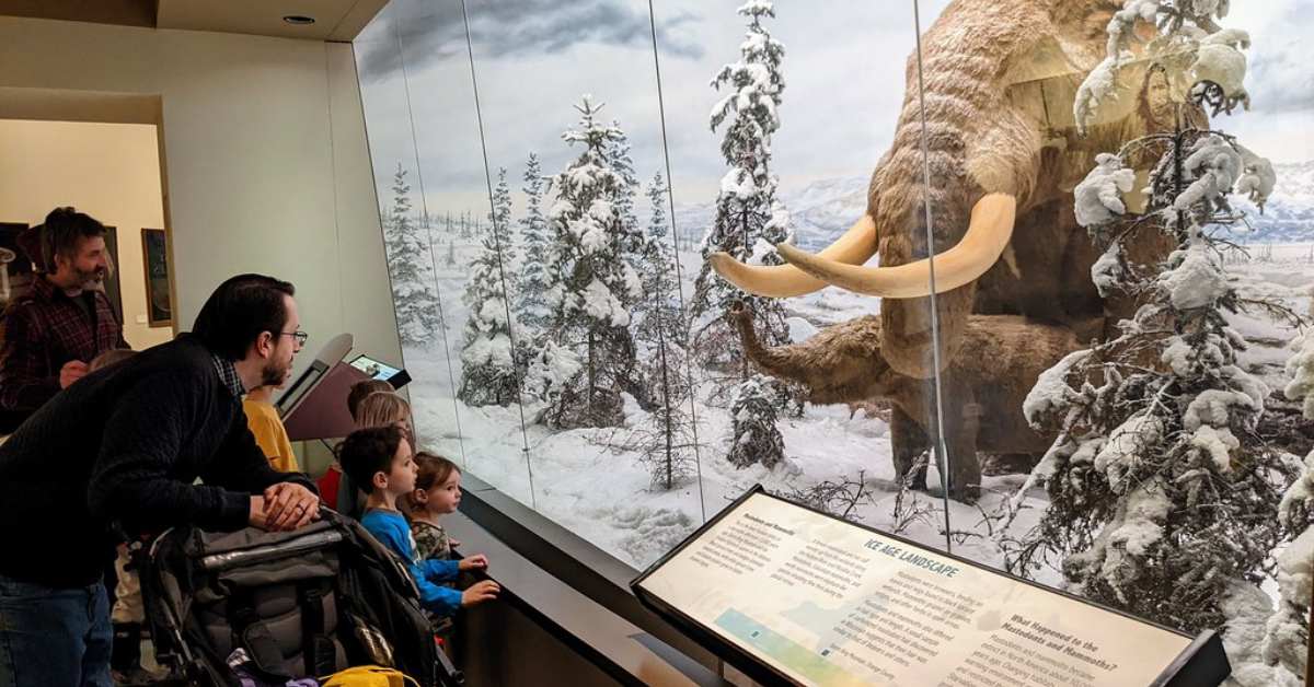 Family with young children looking at a museum exhibit of a Woolly Mammoth