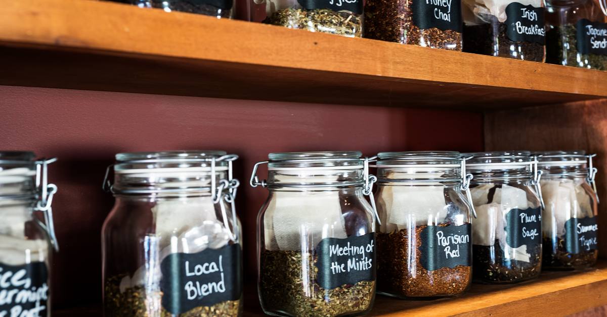 Closeup of a bunch of jars on a shelf labeled with different tea leaves