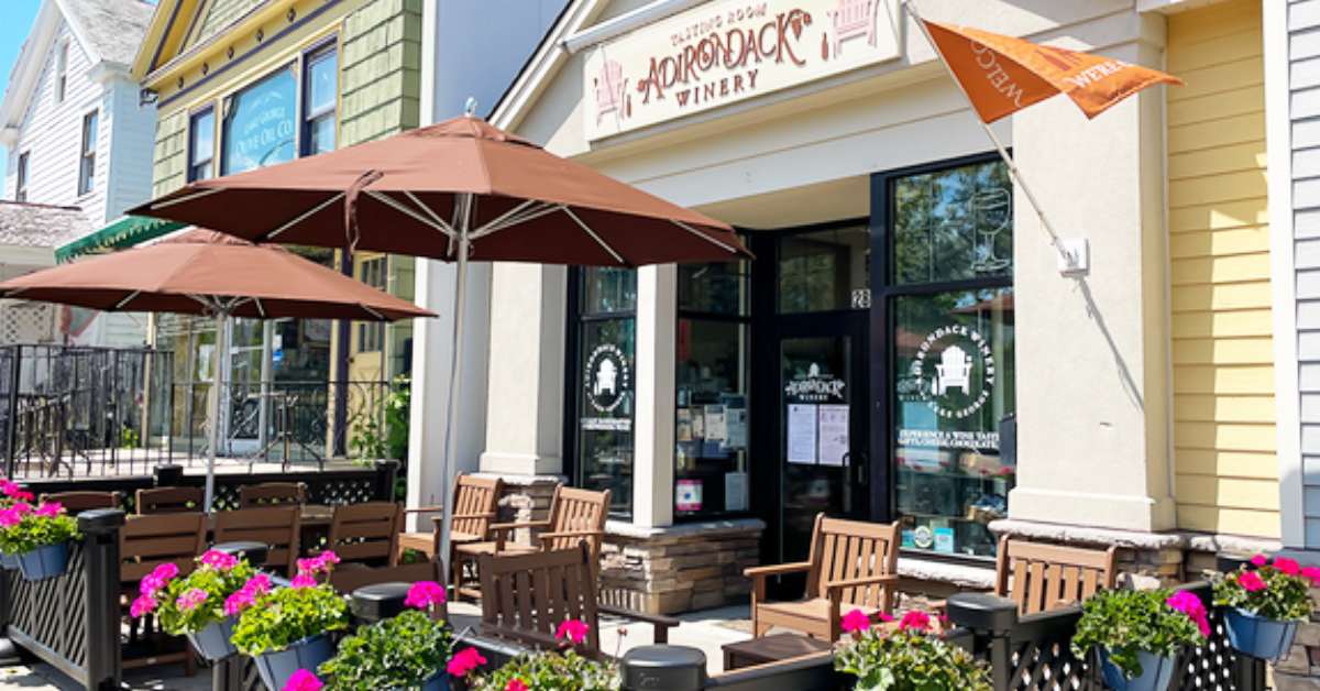 Patio with umbrellas, tables, and colorful flowers in front of Adirondack Winery