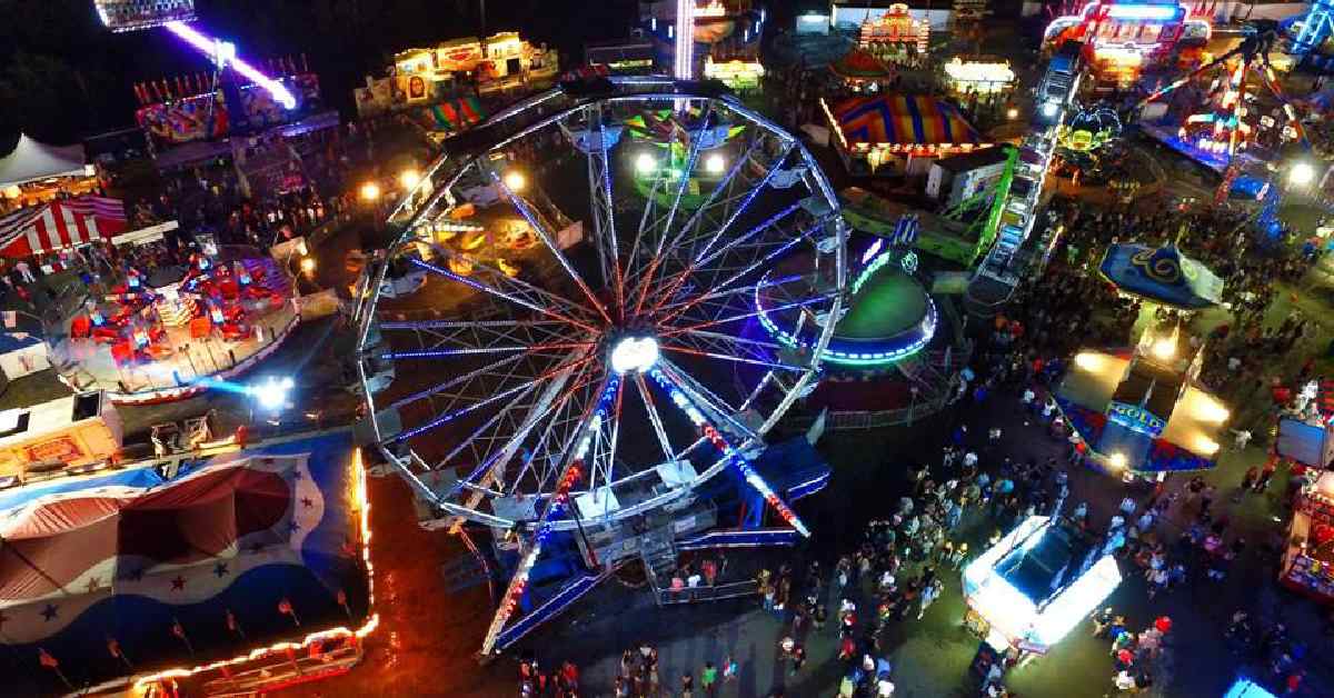 aerial view of a ferris wheel and fair attractions at night