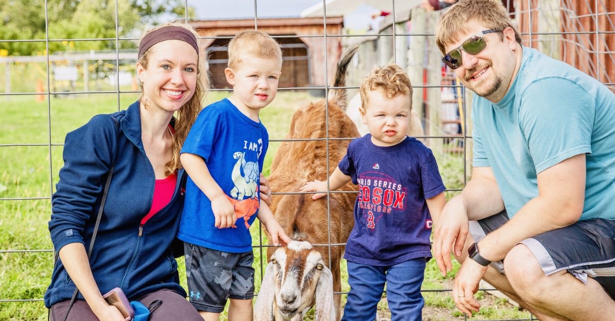 family of four at bowman orchards pose with goat