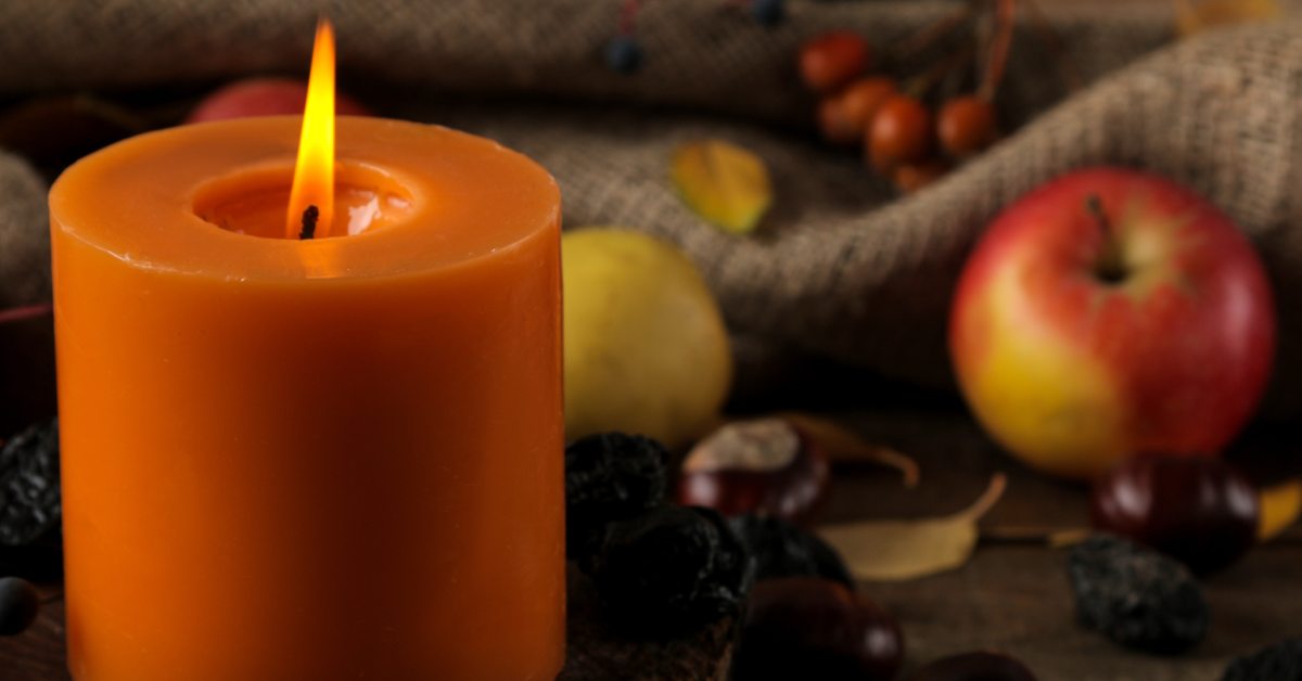 candle in front of fall-ish background with apples