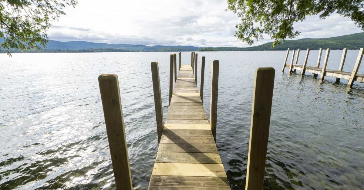 looking out on wooden dock with water and mountains in background