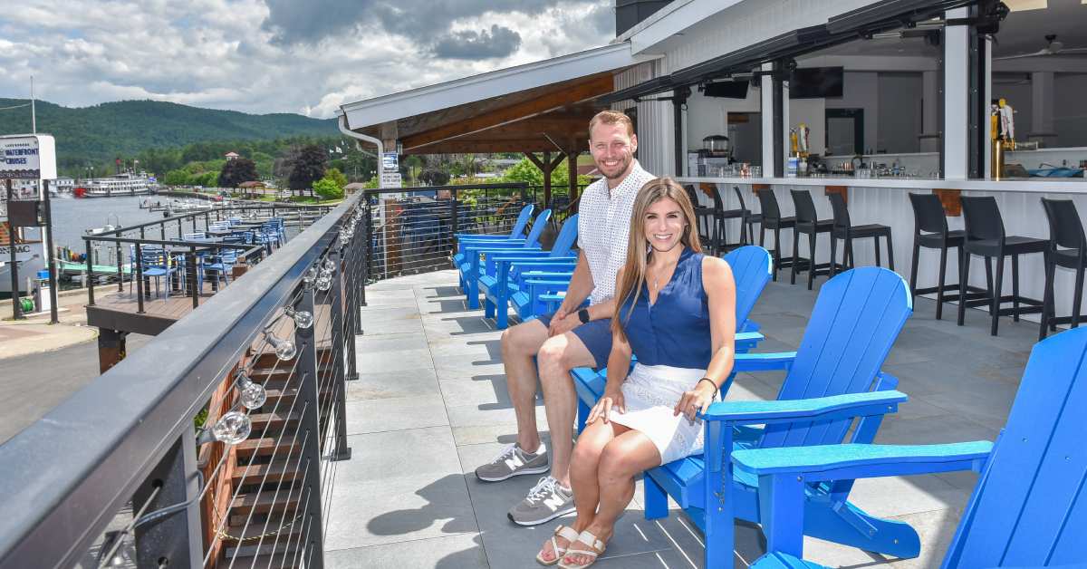 katie and will carson on blue adirondack chairs on restaurant deck