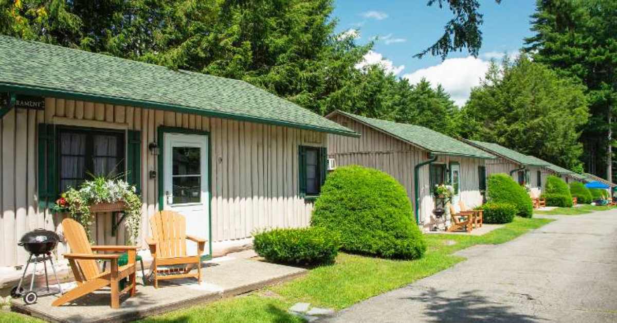 cabins lined up with adirondack chairs, flowers, and a small grill in front of them