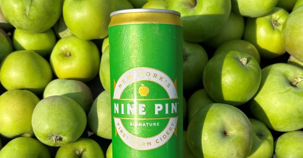 nine pin cider in front of green apples