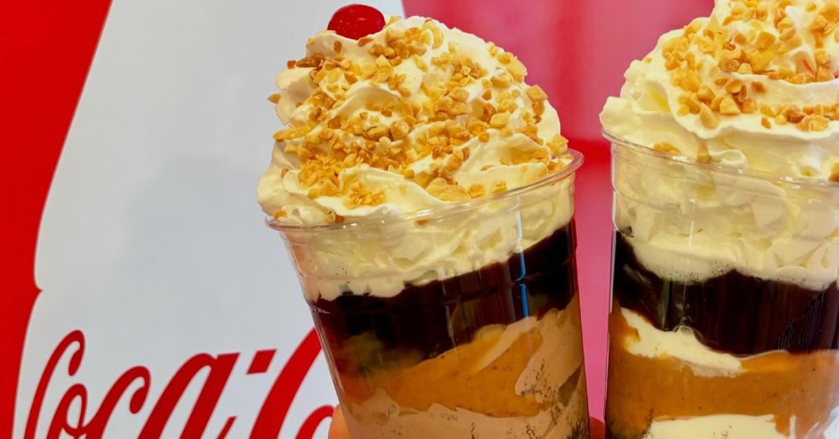 two milkshakes side by side made with chocolate, peanut butter, whipped cream, and nuts