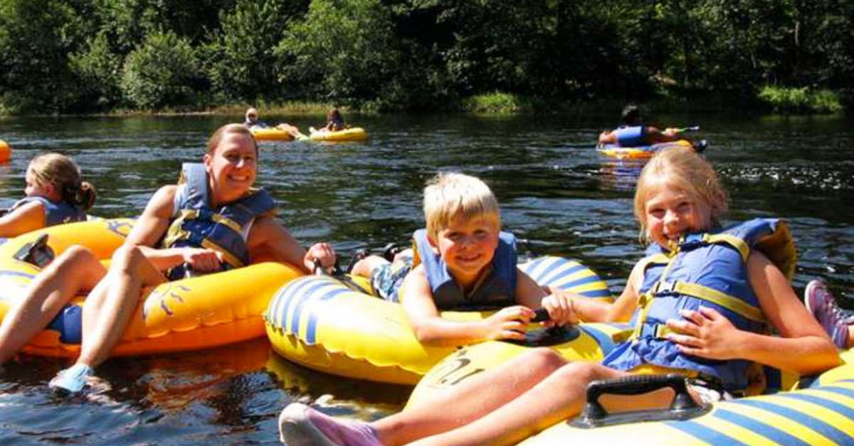 kids and mom in tubes floating in river smiling for picture