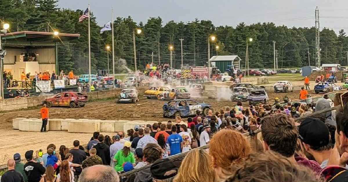 people at a fair watching a demo derby event