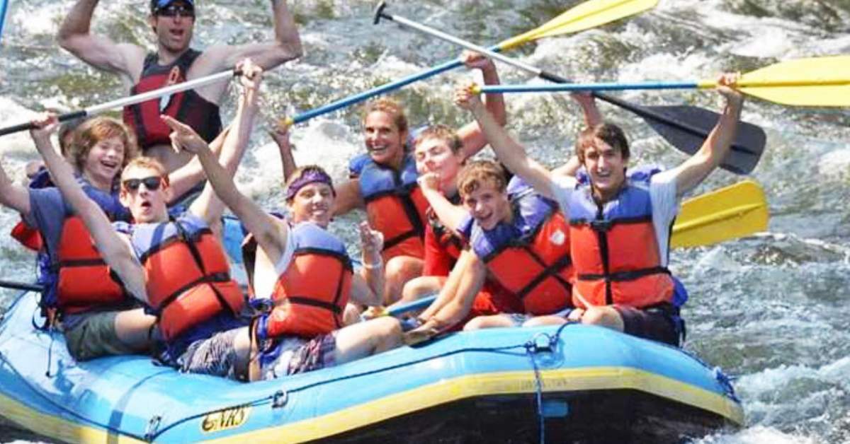 group of people rafting with paddles in the air