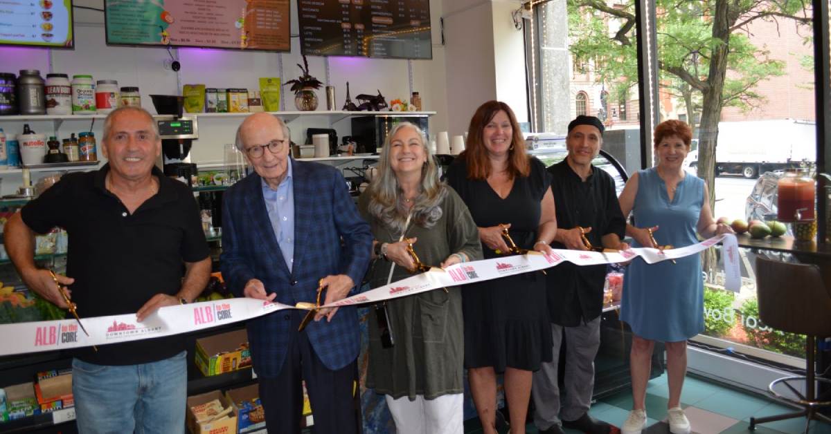 Six people with scissors holding a ribbon for a ribbon cutting ceremony