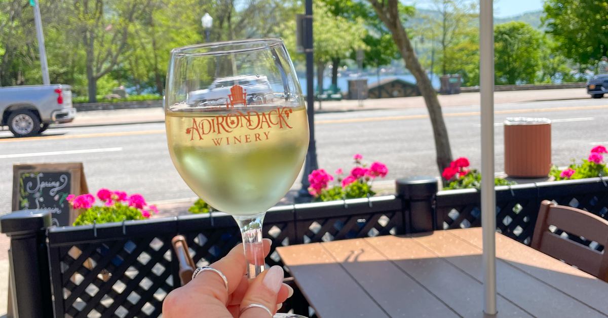 person outdoors holding up a full Adirondack Winery wine glass