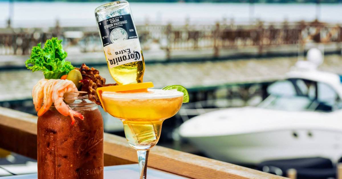 Two cocktails on a dock next to boats and water